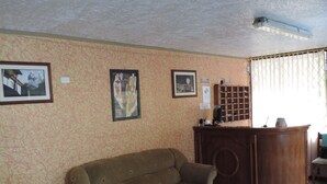 Un salon avec un canapé marron, un bureau en bois et des tableaux encadrés accrochés au mur.