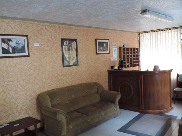 Un salon avec un canapé marron, un bureau en bois et des tableaux encadrés accrochés au mur.