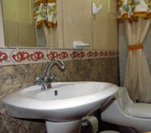 A bathroom with a sink, a mirror, and a toilet.