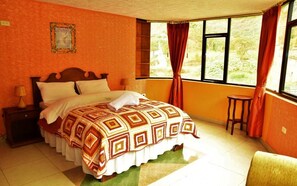 A bedroom with a large bed, a nightstand, a chair, and a window with curtains.
