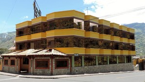 Un immeuble à plusieurs étages, doté d’une façade jaune et d’une petite construction adjacente surmontée d’un toit en tuiles.