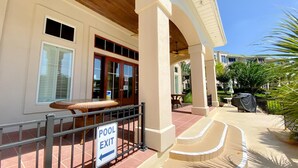 A pool exit sign, a covered patio with a table and chairs, and a staircase leading to a covered area. - Barefoot Resort by Palmetto Vacations (North Myrtle Beach)