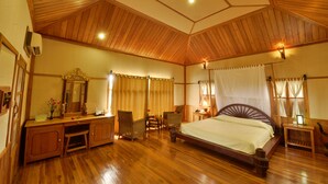 A wooden-paneled room with a bed, a desk, and chairs. - Shwe Inn Tha Floating Resort Hotel (Nyaungshwe)