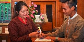 A woman and a man sitting at a wooden table with a map and a pen, in a room with wooden walls and a poster on the wall. - Shwe Inn Tha Floating Resort Hotel (Nyaungshwe)