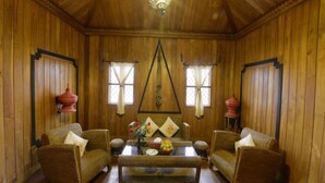 A wooden-paneled room with two wicker armchairs, a coffee table, and a chandelier. - Shwe Inn Tha Floating Resort Hotel (Nyaungshwe)
