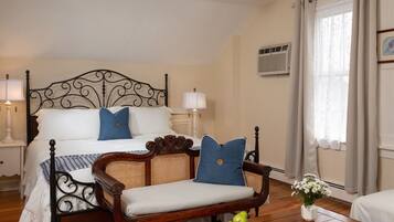 A bedroom with a four-poster bed, a wooden bench, and a bedside table with a lamp.