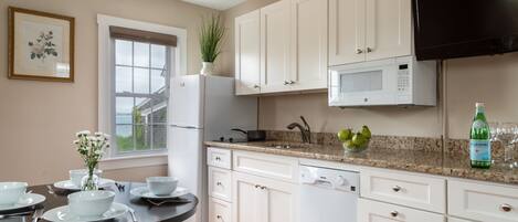 A modern kitchen with white cabinets, a microwave, and a dining area with a table set for four.