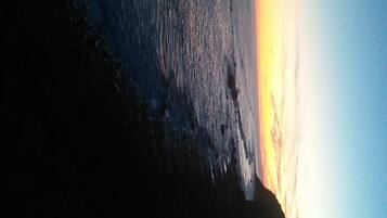 A sunset over a body of water with a rocky shoreline.