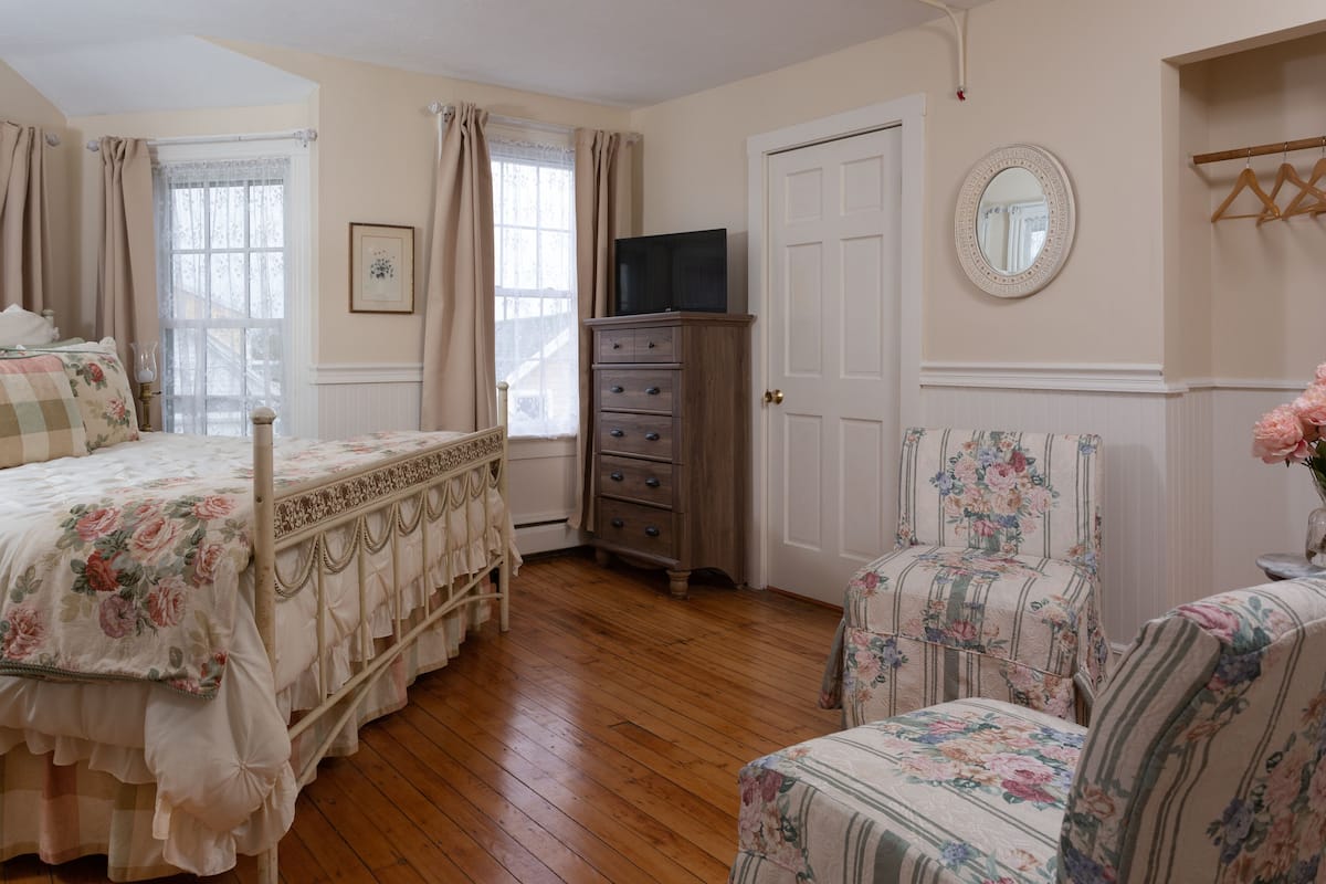 Une chambre à coucher avec un lit, une commode, une chaise et un téléviseur.