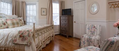 A bedroom with a bed, dresser, chair, and a television.