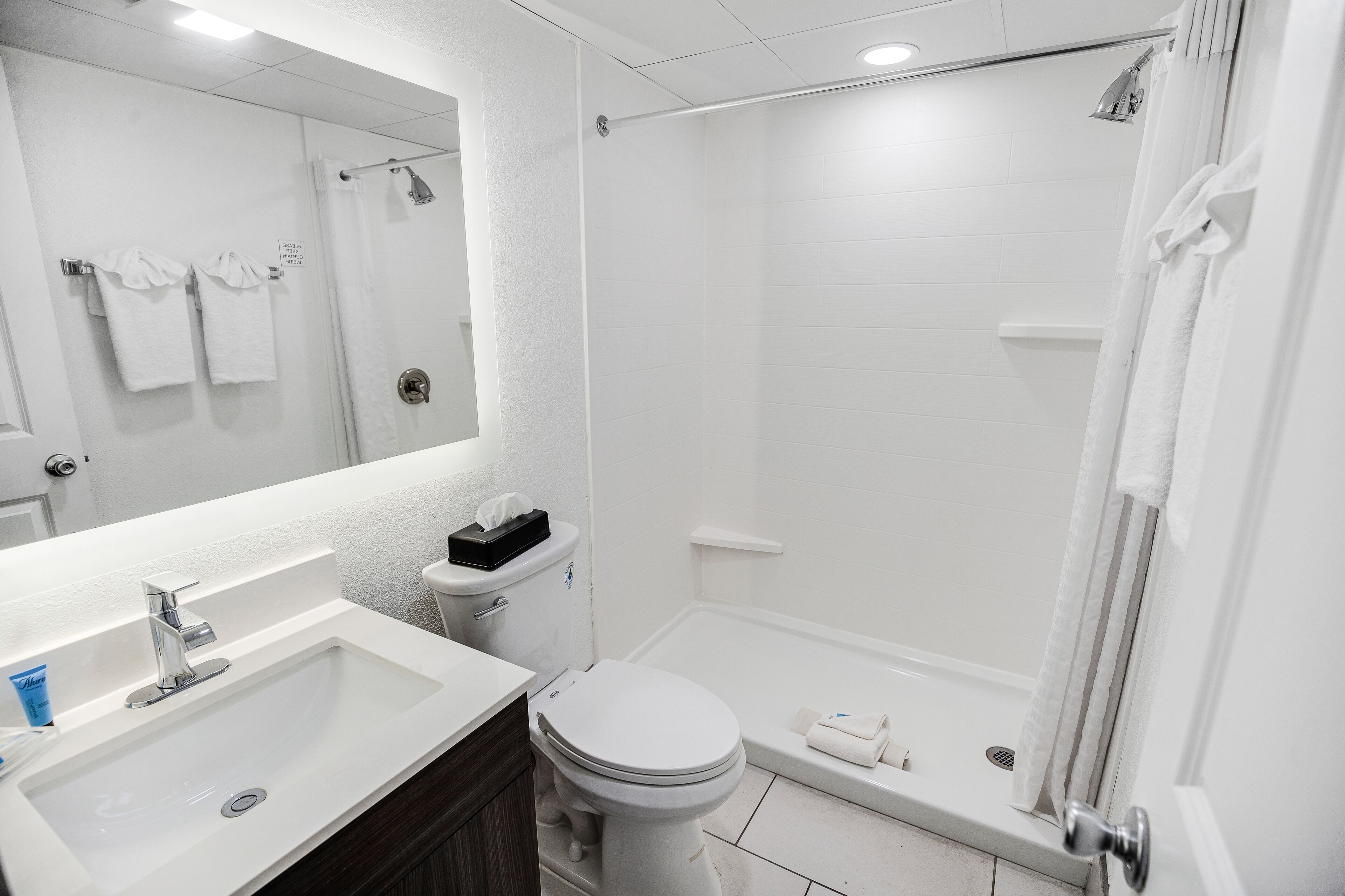 Un baño moderno con lavamanos, inodoro y ducha.