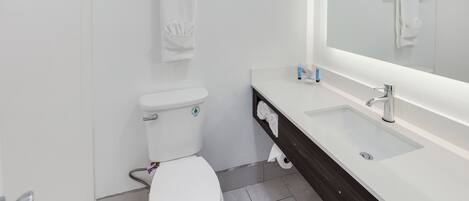 A modern bathroom with a white toilet, a large mirror, and a dark wooden vanity.