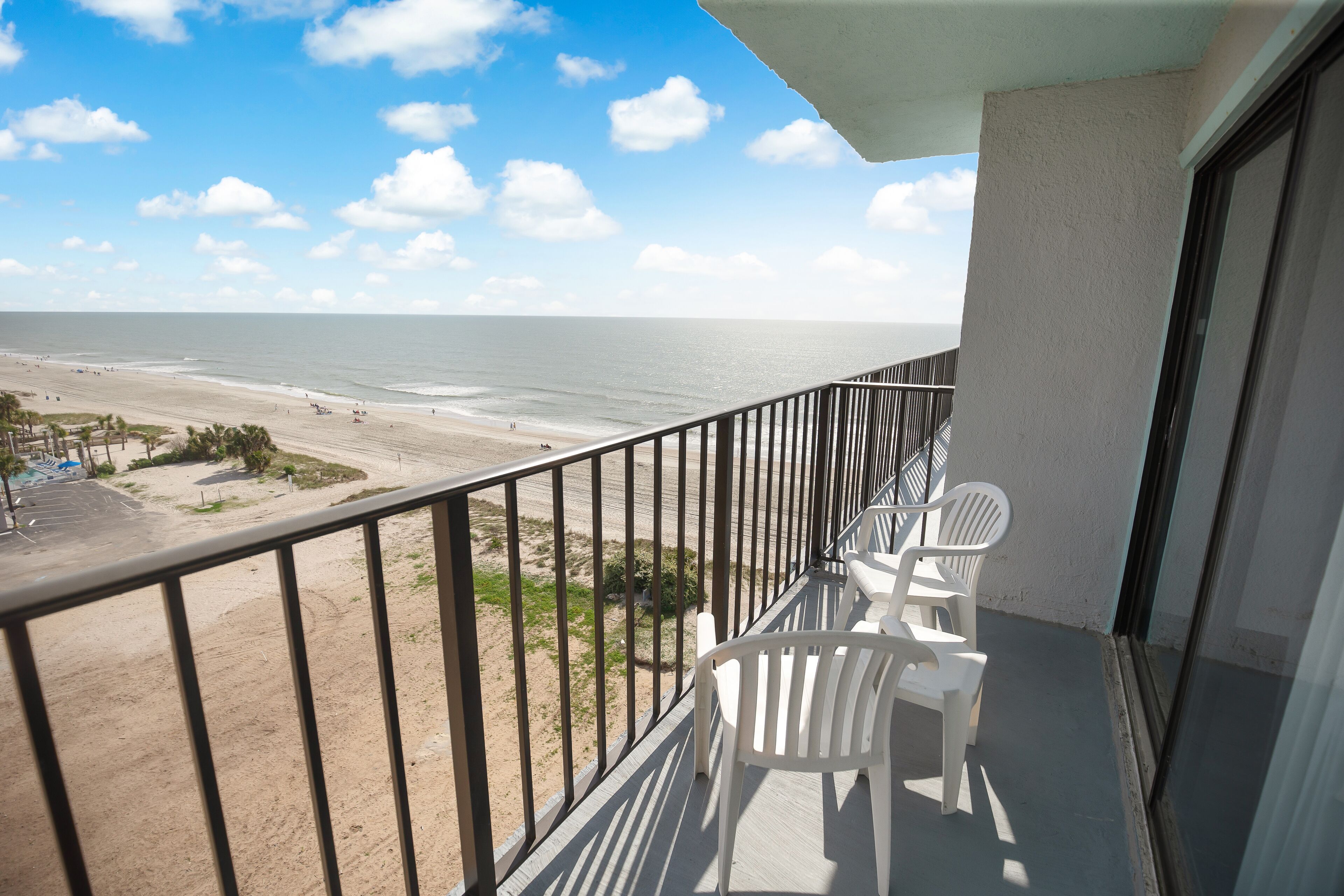 A balcony with a view of the beach and ocean.