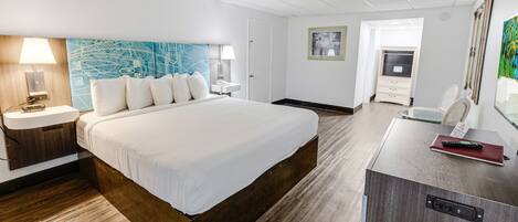 A hotel room with a large bed, bedside tables, a desk with a chair, and a wardrobe.