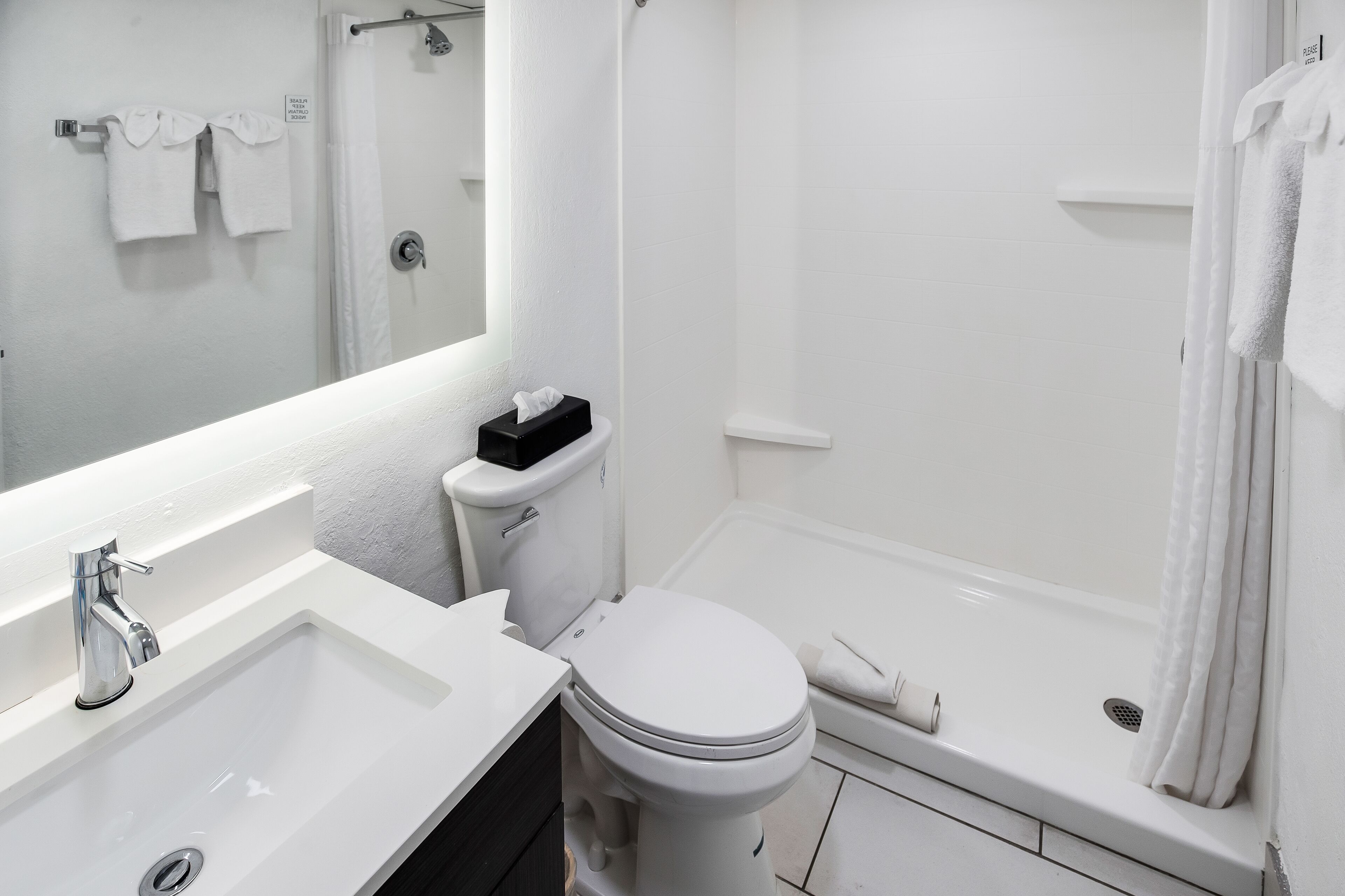 Une salle de bain moderne avec un lavabo, des toilettes et une baignoire, le tout de couleur blanche.
