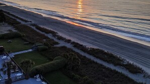 A beach view with a sunset, a pool, and outdoor seating. - Tropical Seas Hotel (Myrtle Beach)