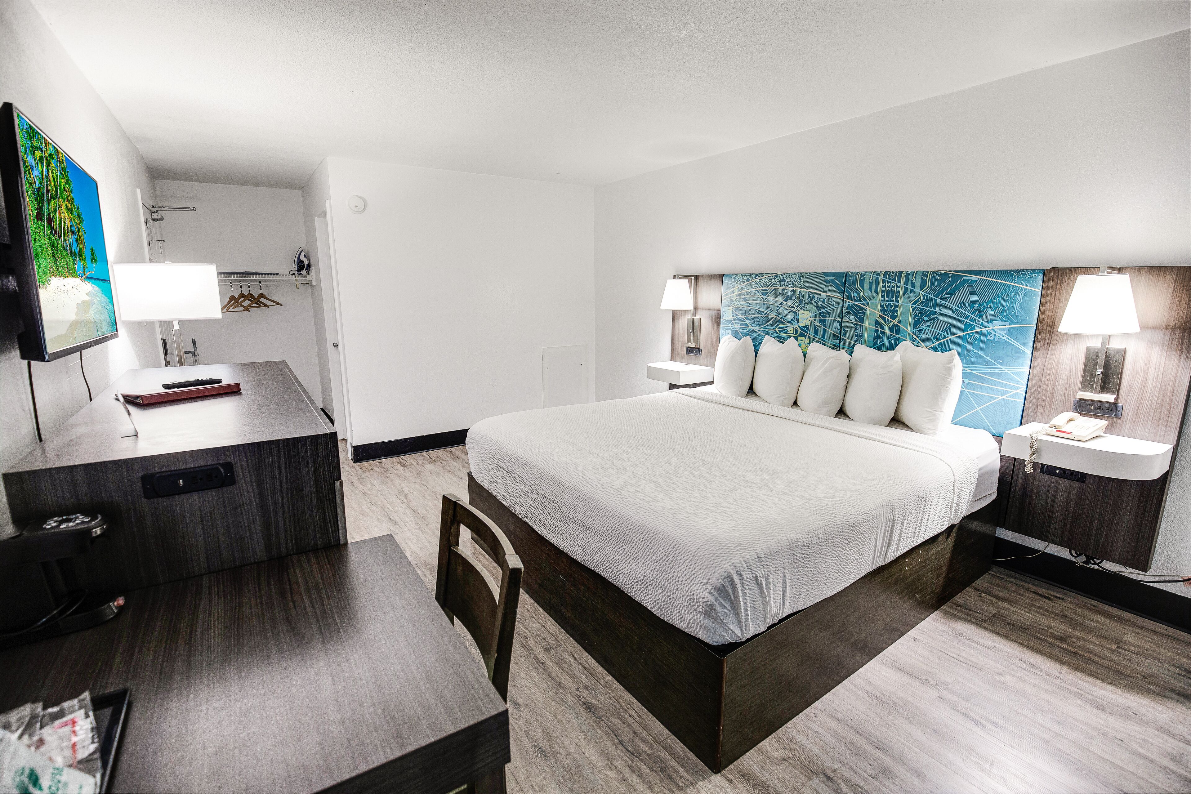 Une chambre d’hôtel moderne dotée d’un grand lit, d’un bureau, d’une télévision et d’une salle de bain avec un miroir et un porte-serviettes.