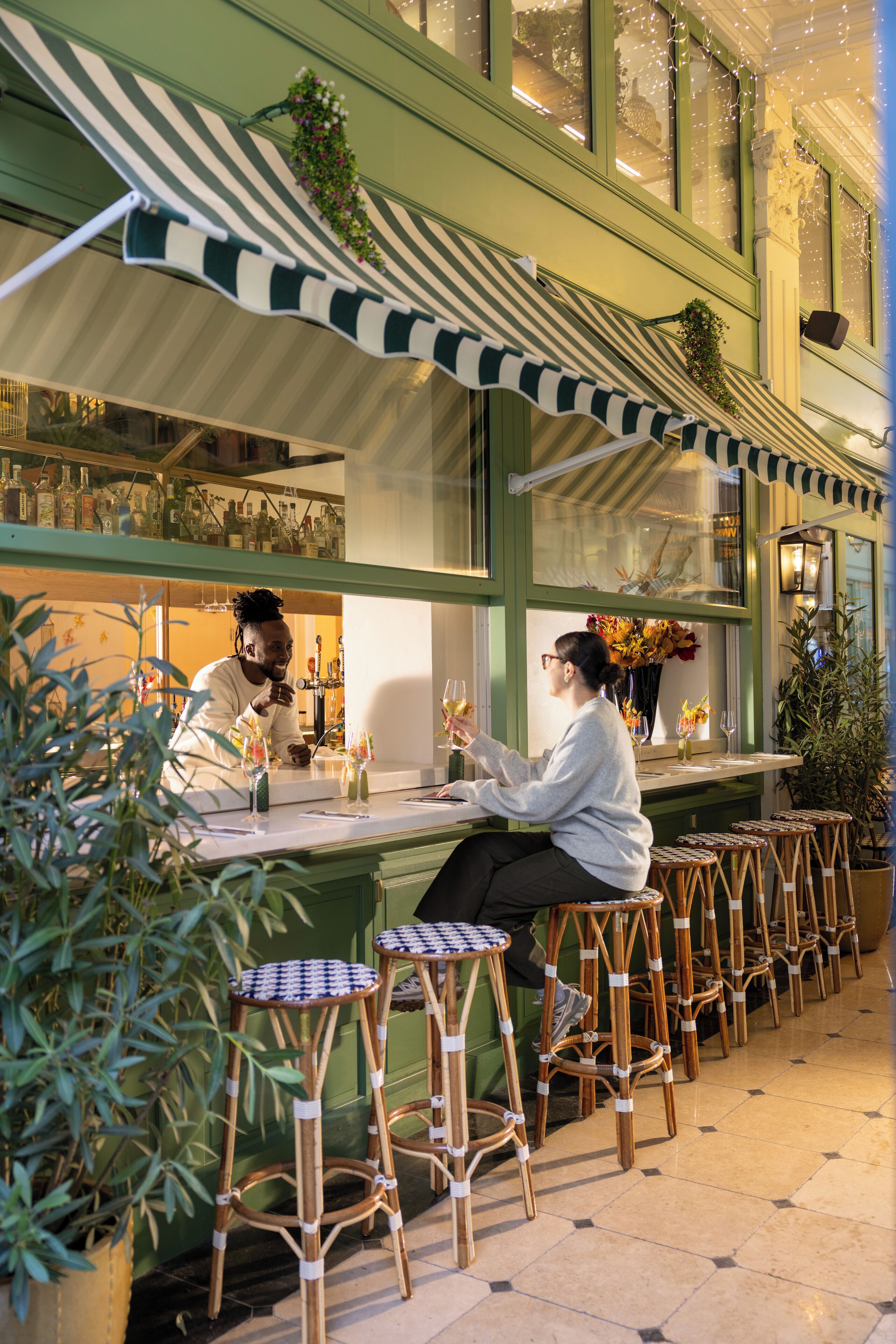 A bar area with wicker chairs and a striped awning.