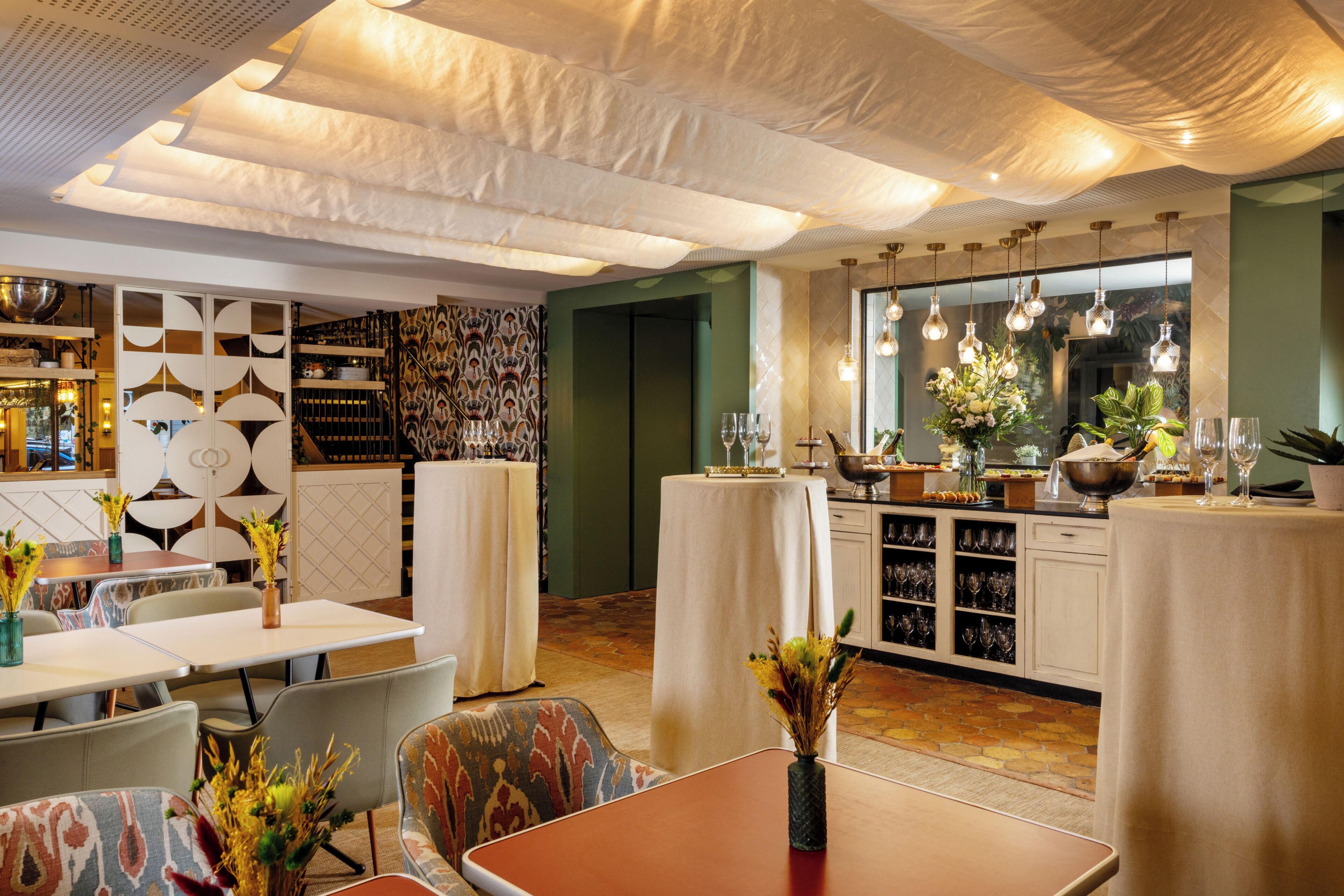 A restaurant interior with tables, chairs, decorative vases, and hanging light fixtures.