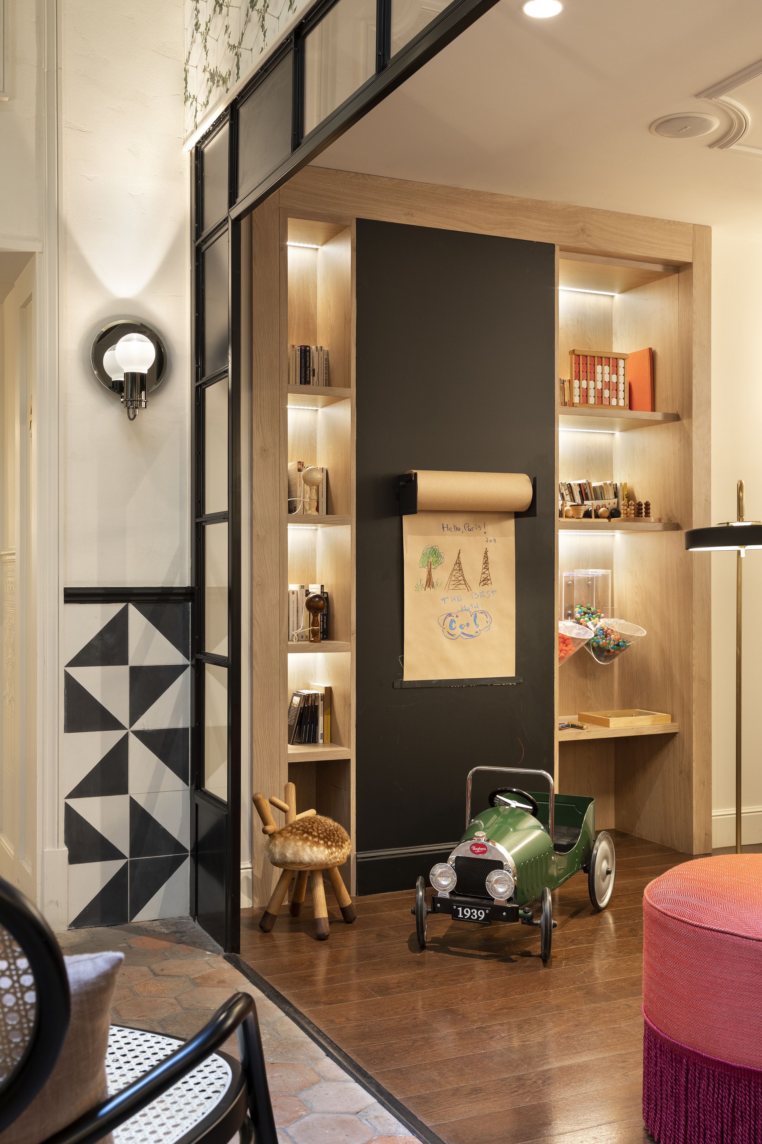 A modern interior with a wooden bookshelf, a vintage car model, and a patterned floor.