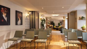 Une salle de conférence avec des rangées de chaises, un plancher en bois et des panneaux décoratifs sur les murs.