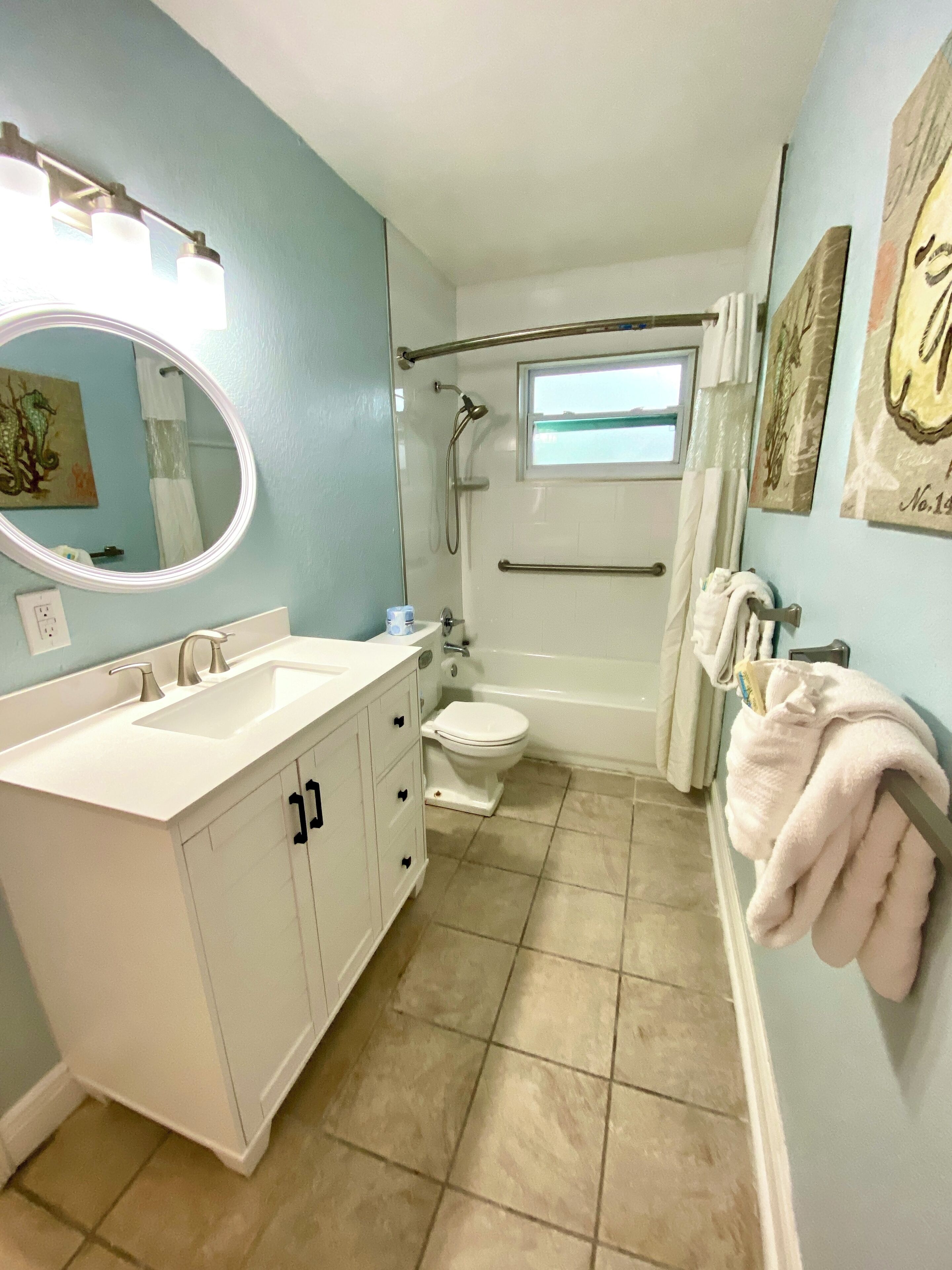 A bathroom with a white vanity, a bathtub, a toilet, and a shower.
