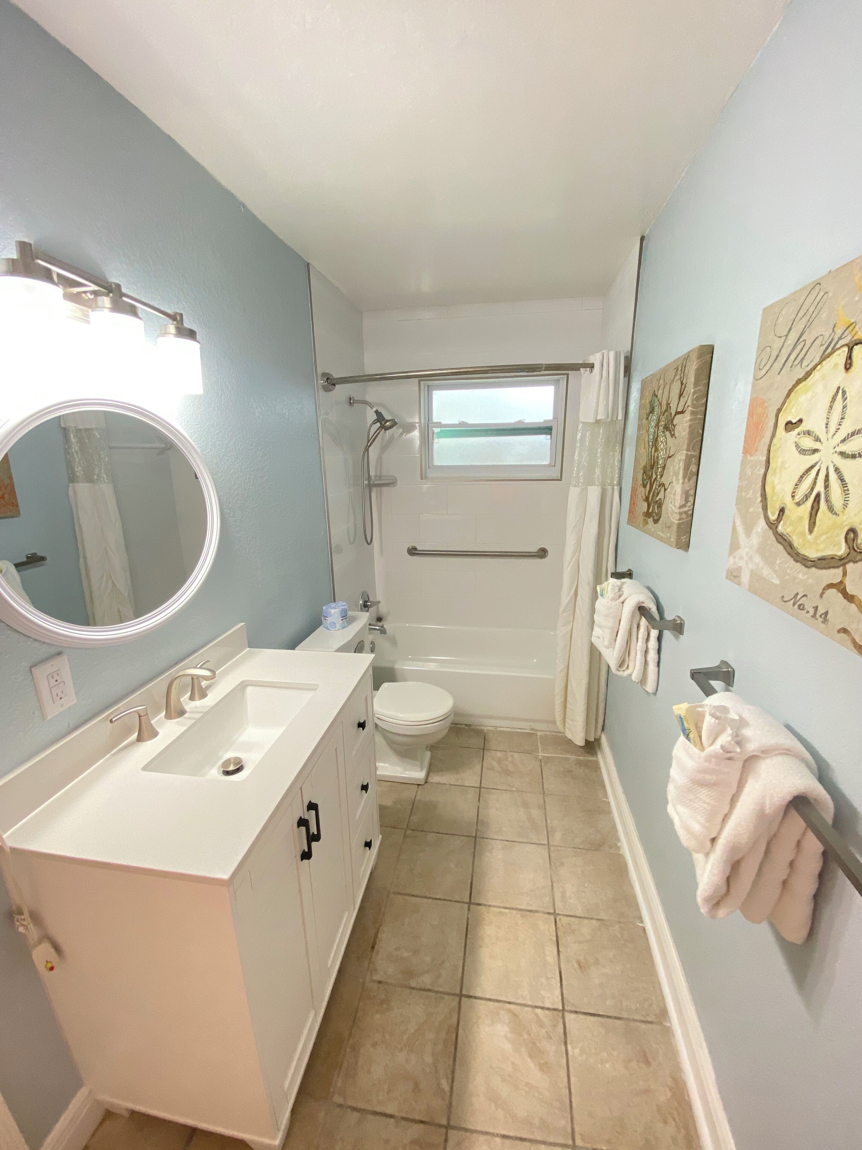 A bathroom with a sink, mirror, toilet, and bathtub.