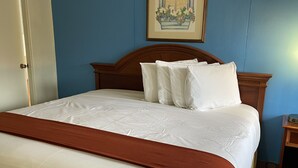 A neatly made bed with white linens and a brown accent, a wooden headboard, and a framed picture on the wall. - Ephrata Inn Motel (Ephrata)