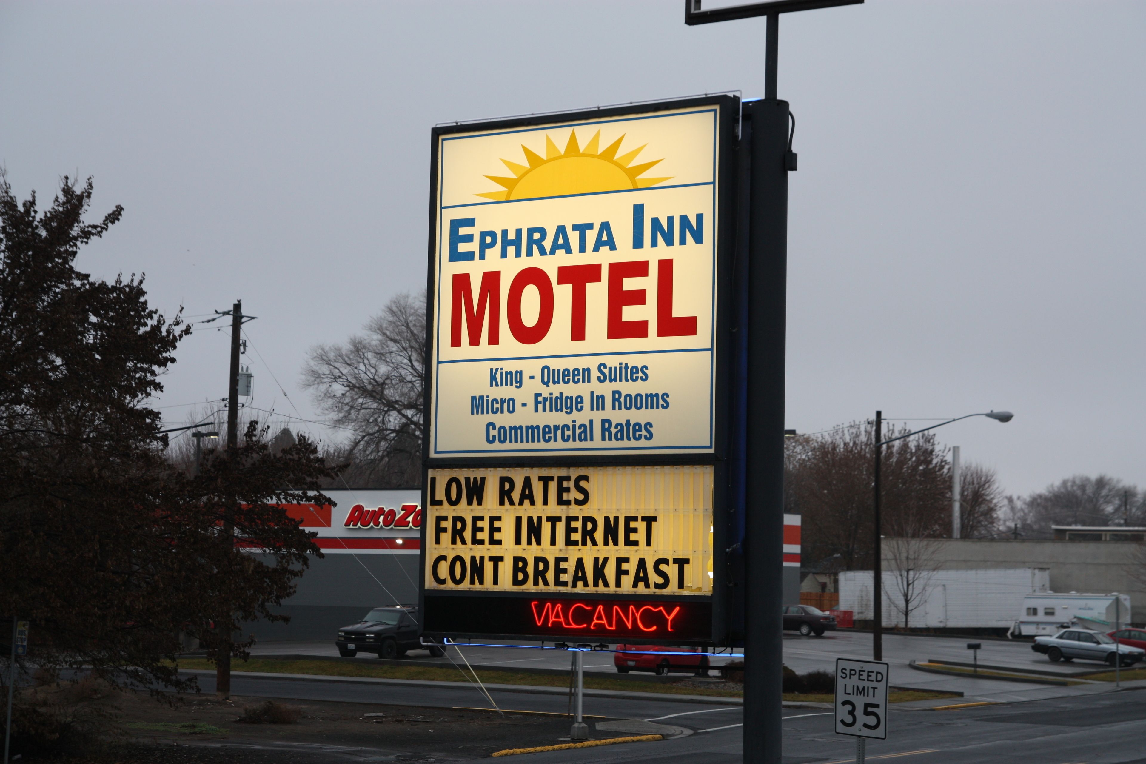 A motel sign advertising King-Queen suites, micro-fridge in rooms, commercial rates, low rates, free internet, and a breakfast option.