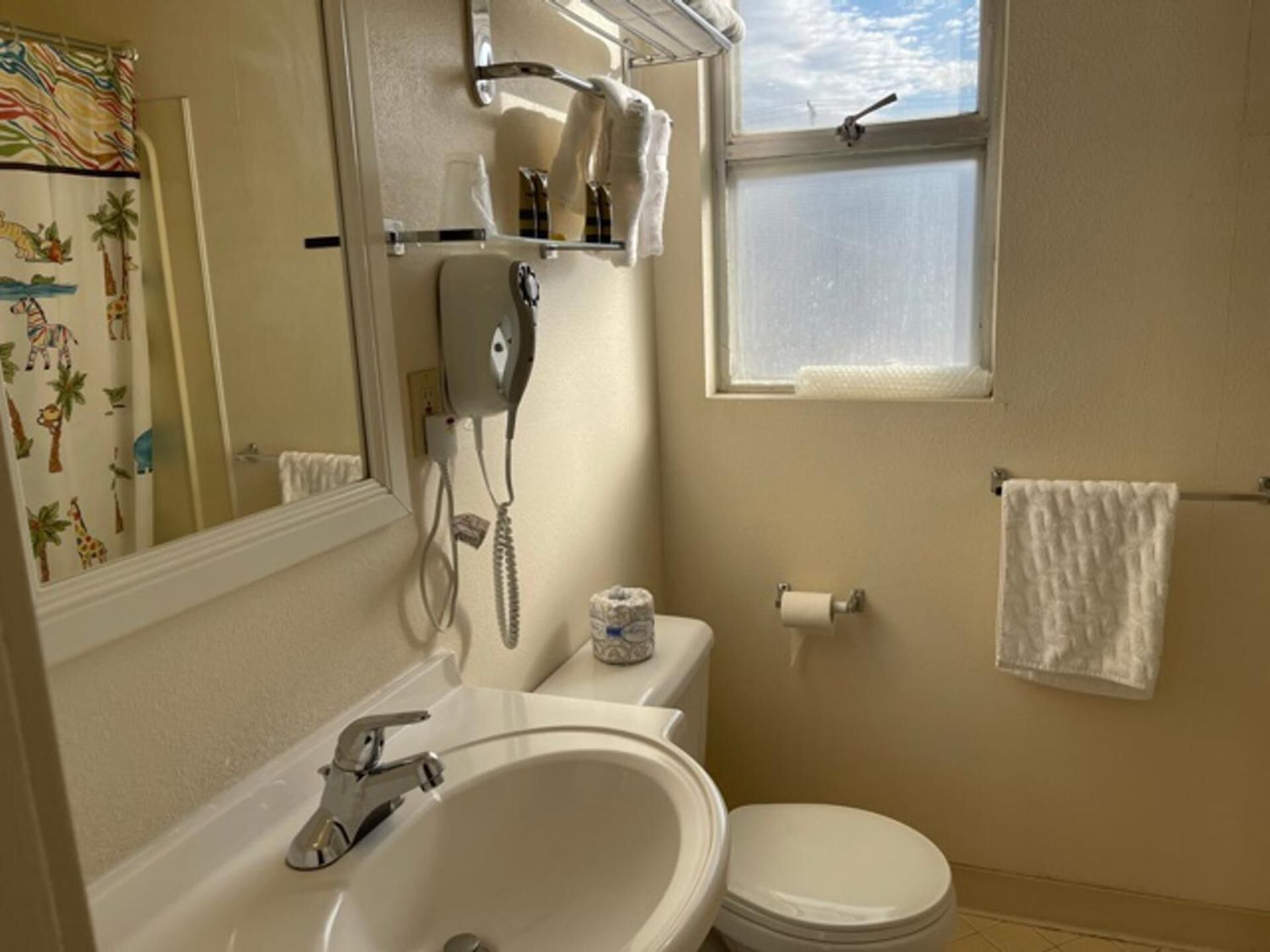A bathroom with a white sink, toilet, and a window above the toilet.