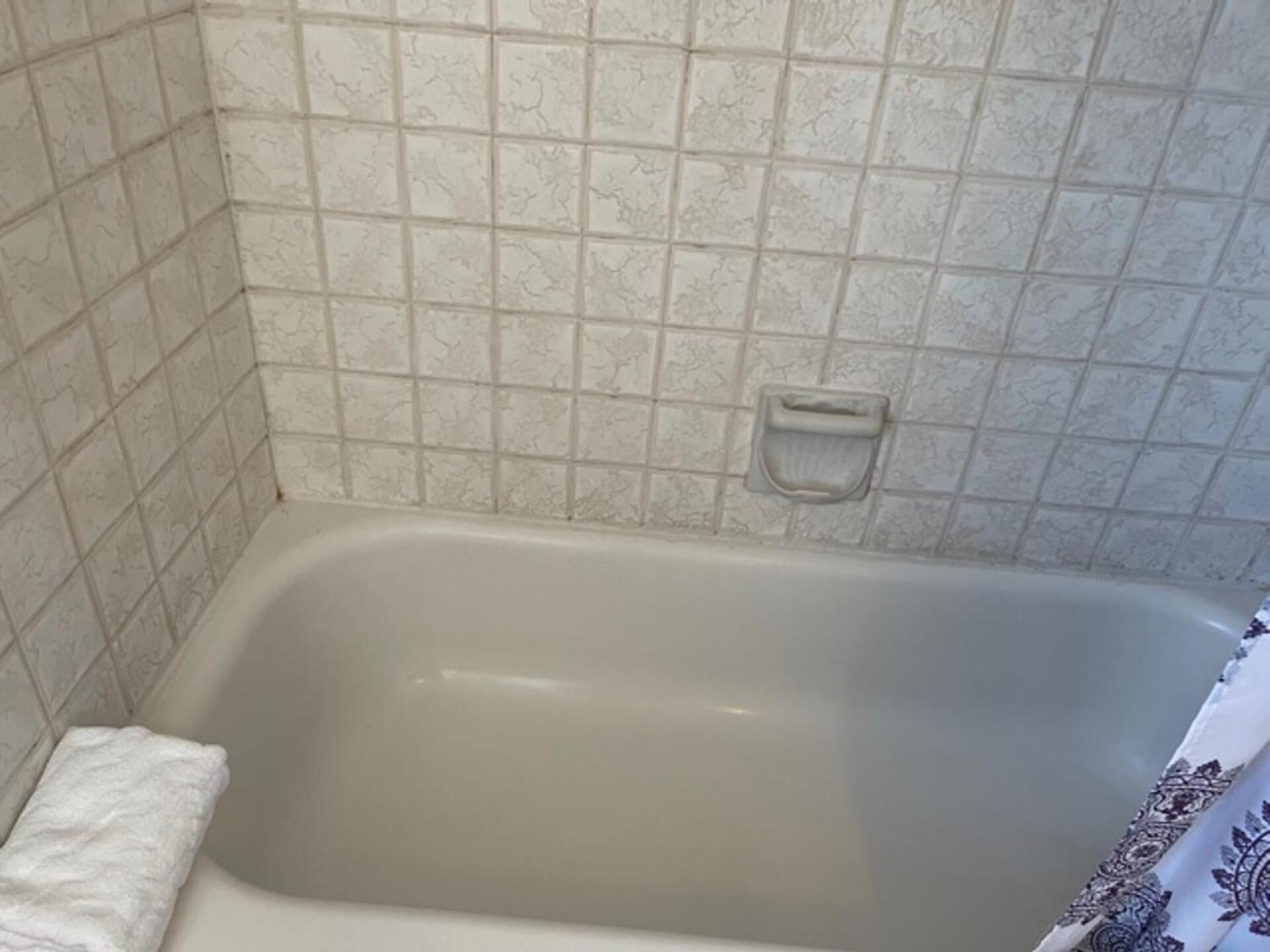 A bathroom with a bathtub, tiled walls, and a towel rack.