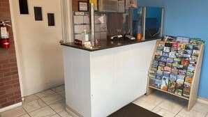 A reception desk with a bulletin board displaying travel guides, a fire extinguisher, and a small window. - Ephrata Inn Motel (Ephrata)