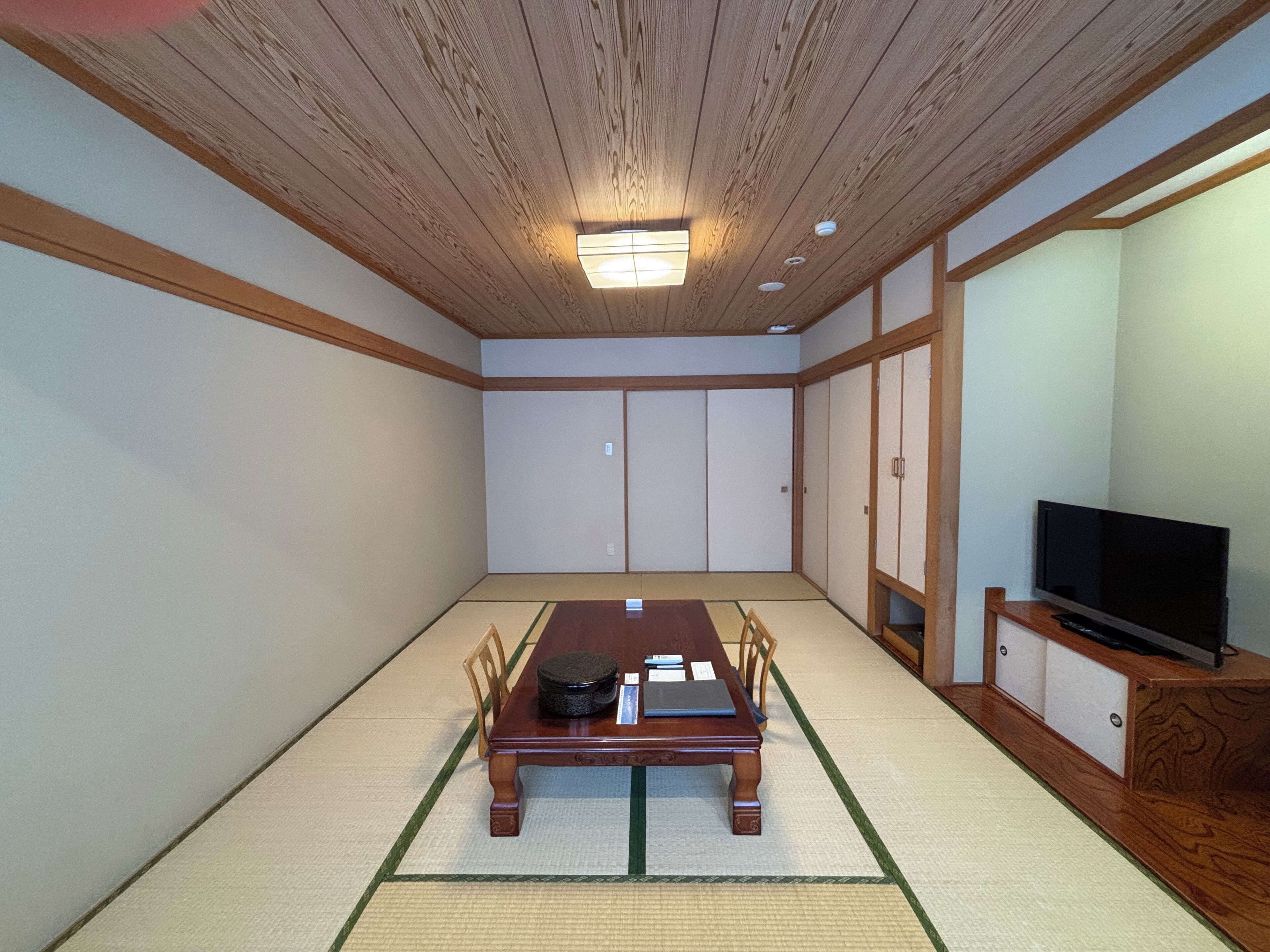 Perinteinen japanilaistyylinen huone, jossa on tatamimatto, matala puupöytä ja liukuseinäovet.