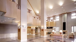 A spacious lobby with a high ceiling, multiple seating areas, and a central decorative rug.