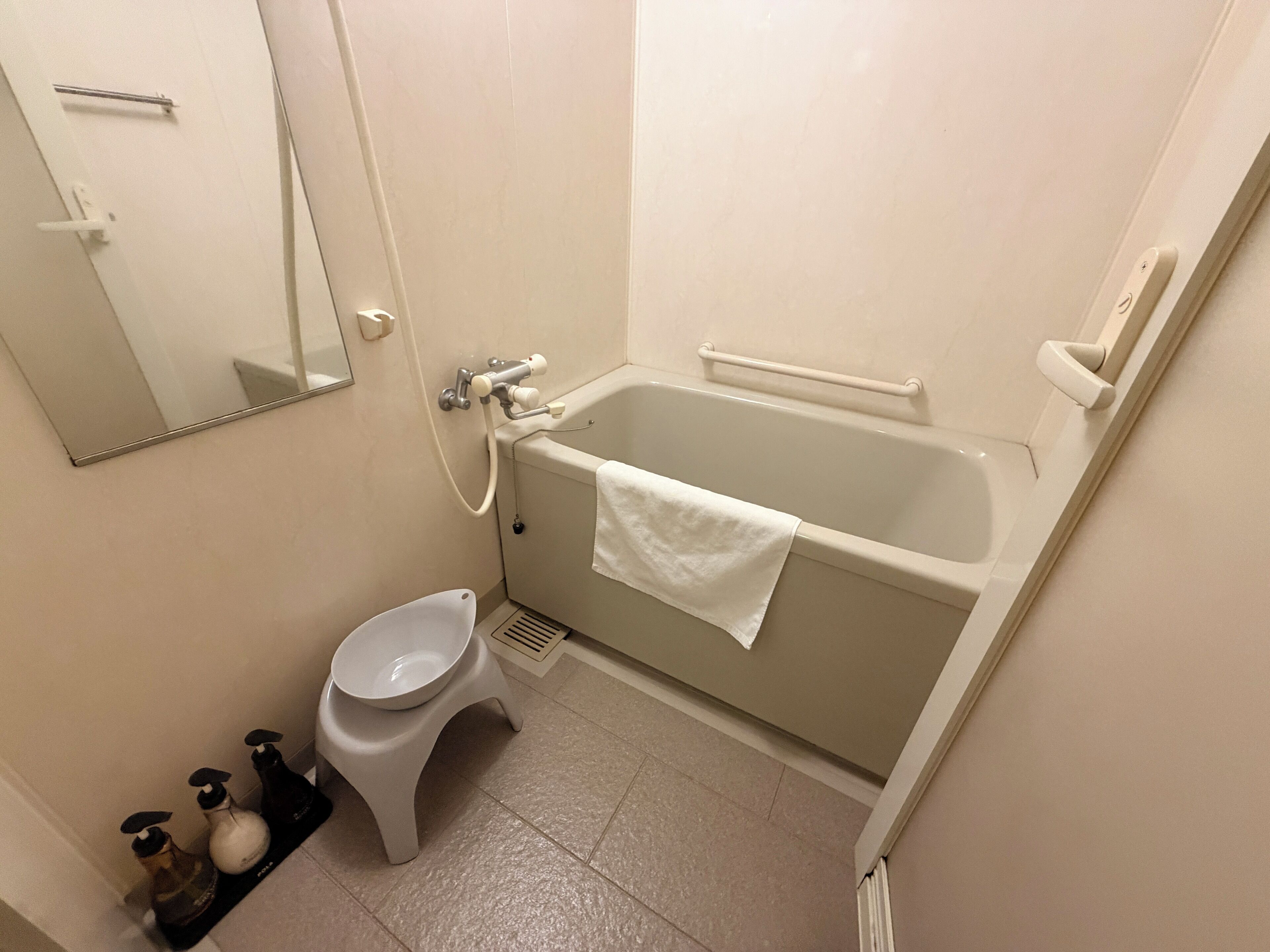 A small bathroom with a bathtub, toilet, and a mirror.