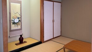A traditional Japanese room with tatami flooring, a sliding door, a small table, and a vase.