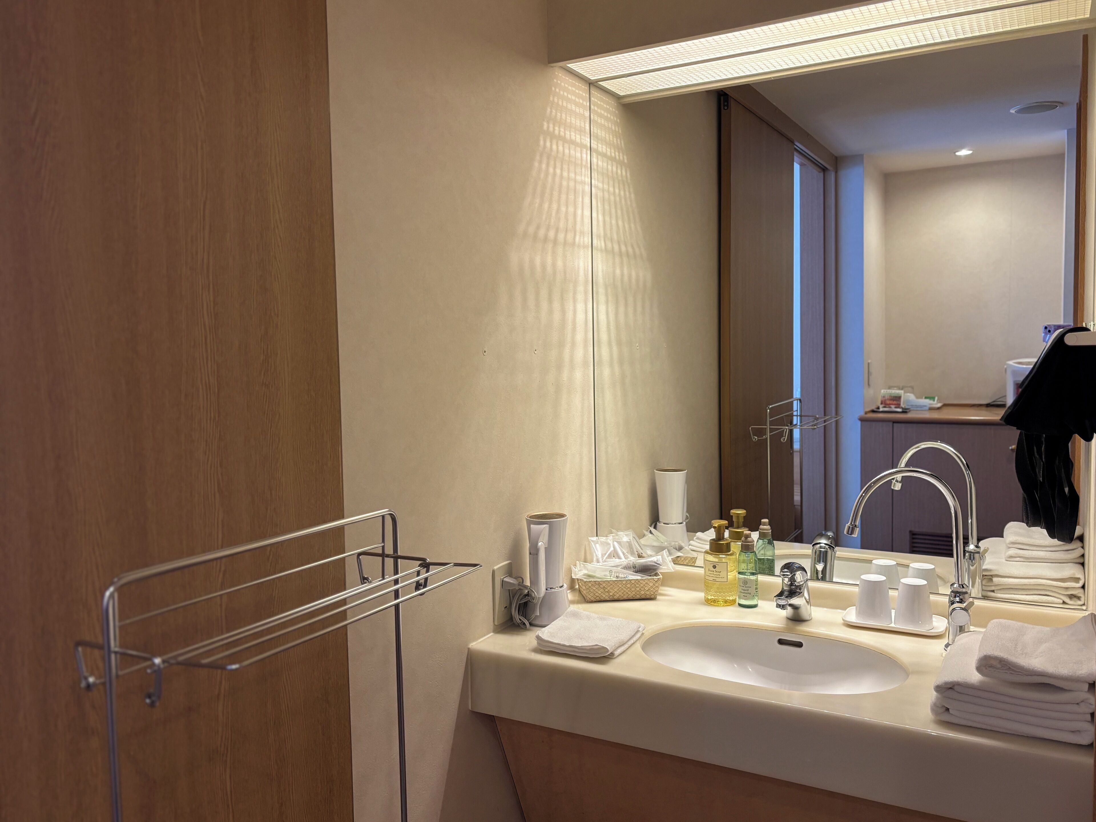 Un baño moderno con lavamanos, espejo, toallero y artículos de aseo.