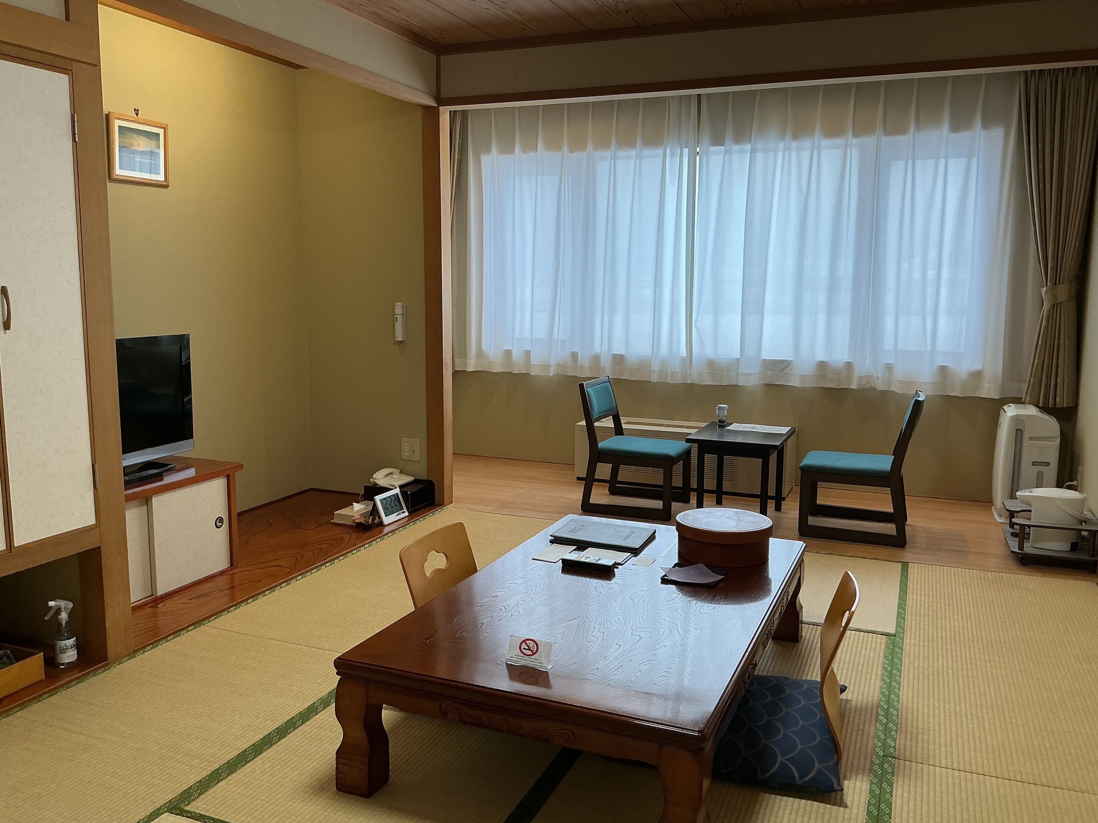 Um quarto japonês tradicional com tatames, uma mesa de madeira, uma televisão e um futon.