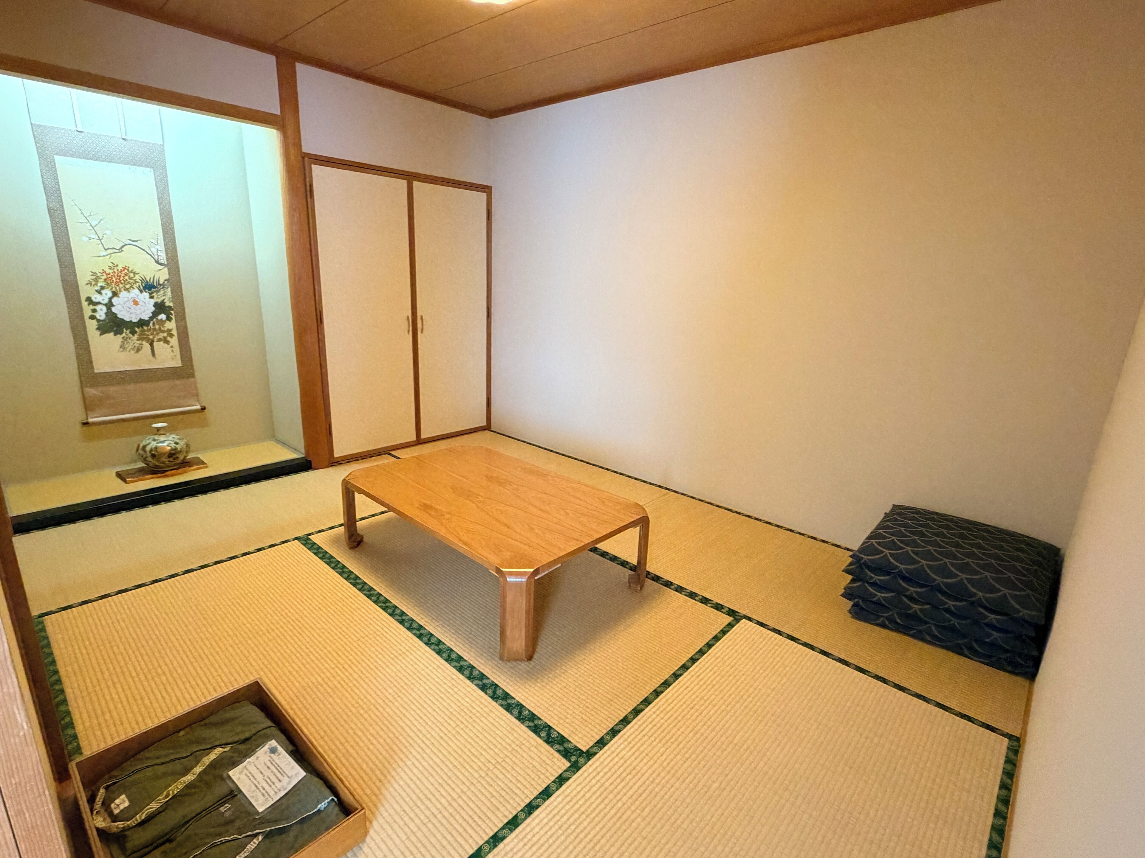 A traditional Japanese room with tatami flooring, a low wooden table, a shoji screen, and a futon bed.
