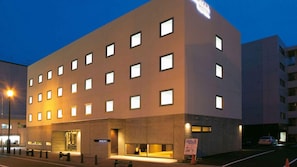 A modern hotel building with multiple windows and a well-lit entrance. - Iwamizawa Hotel 5 Jo (Iwamizawa)