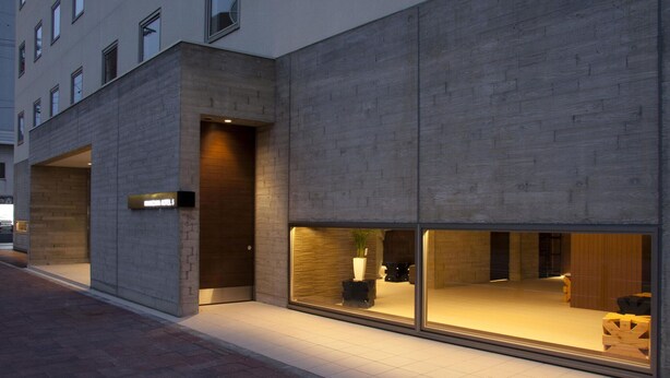 Een modern hotelgebouw met grote ramen, een duidelijke ingang en een bord met de naam van het hotel.