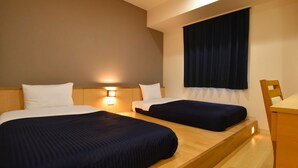 Een hotelkamer met twee bedden, een nachtkastje, een raam met gordijnen en een wandlamp.