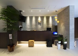 A modern reception area with a flat-screen TV, a wooden reception desk, and a digital display.