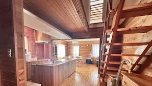 A wooden cabin interior with a kitchen, dining area, and a loft bedroom. - Niseko Hirafu Izumikyo Rental Cottage (Kutchan)
