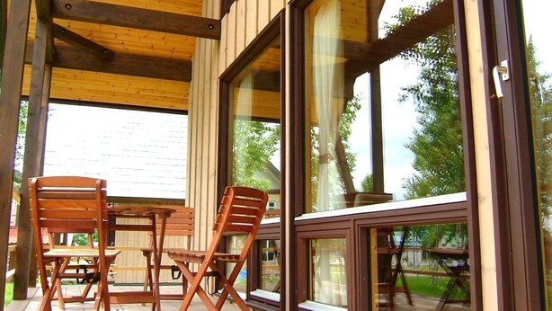An outdoor patio with wooden furniture and large windows. - Niseko Hirafu Izumikyo Rental Cottage (Kutchan)