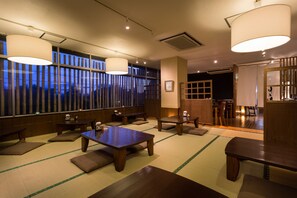 A traditional Japanese room with tatami flooring, low tables, and sliding doors.