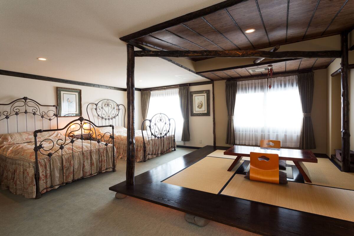 A traditional Japanese-style room with tatami flooring, a low wooden table, and two tatami mats with cushions.