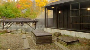 A traditional Japanese onsen with a wooden bathhouse and a wooden deck. - Niseko Annupuri Onsen Yugokorotei (Niseko)