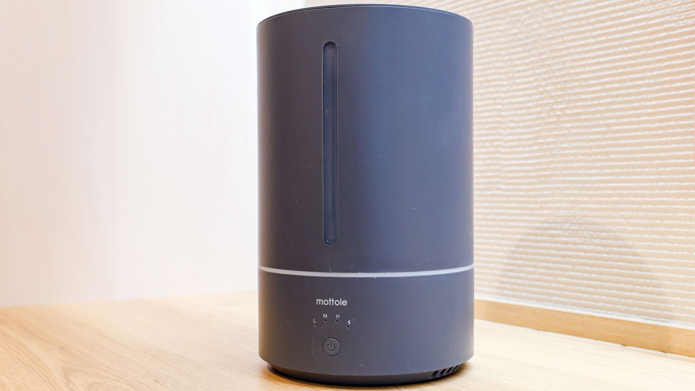 A cylindrical, dark-colored device with the brand name 'mottole' on its side, a power button, and a small display.