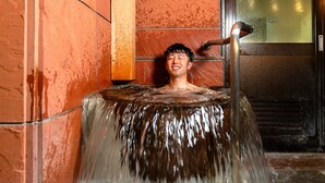 A person in a hot spring with a wooden structure and a metal railing. - Obihiro Tennen Onsen Fukui Hotel (Obihiro)